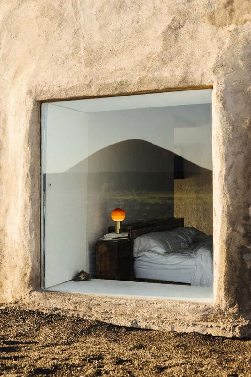 Orange Marset Dipping Light table lamp in a bedroom seen through the window. 